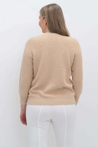 Back view of a woman wearing a beige cotton sweater with ribbed cuffs and hem