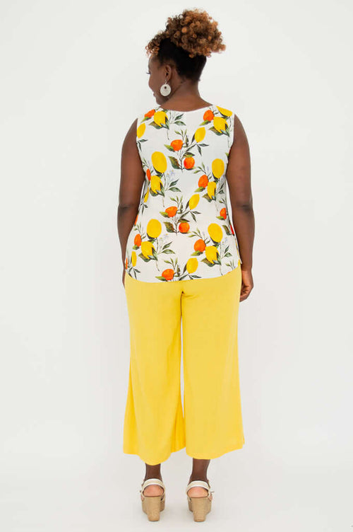 Back view of woman wearing sleeveless lemon and orange print top with yellow wide-leg pants