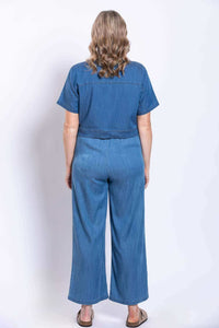 Back view of a cropped blue denim jacket paired with matching blue denim pants