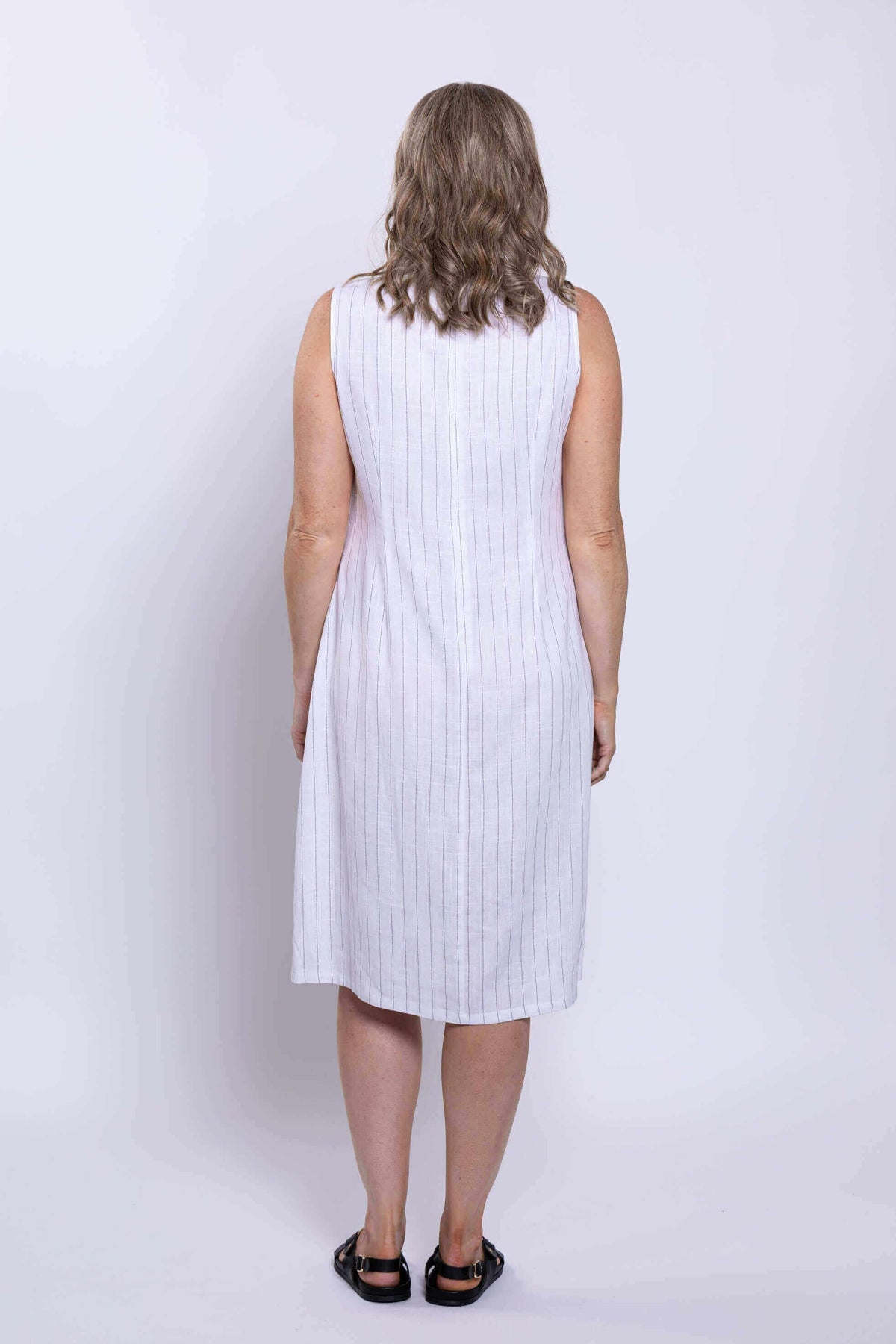 Back view of woman in sleeveless white dress with vertical stripes