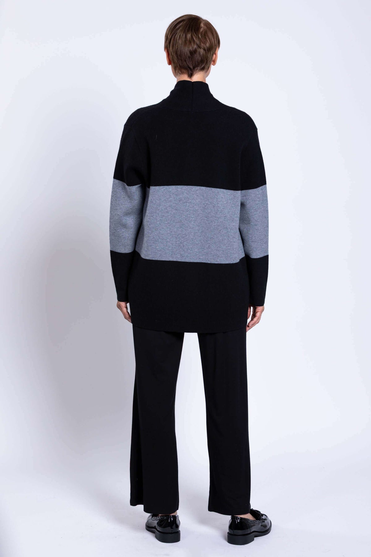 Rear view of woman wearing black and grey colour block sweater showing the back design
