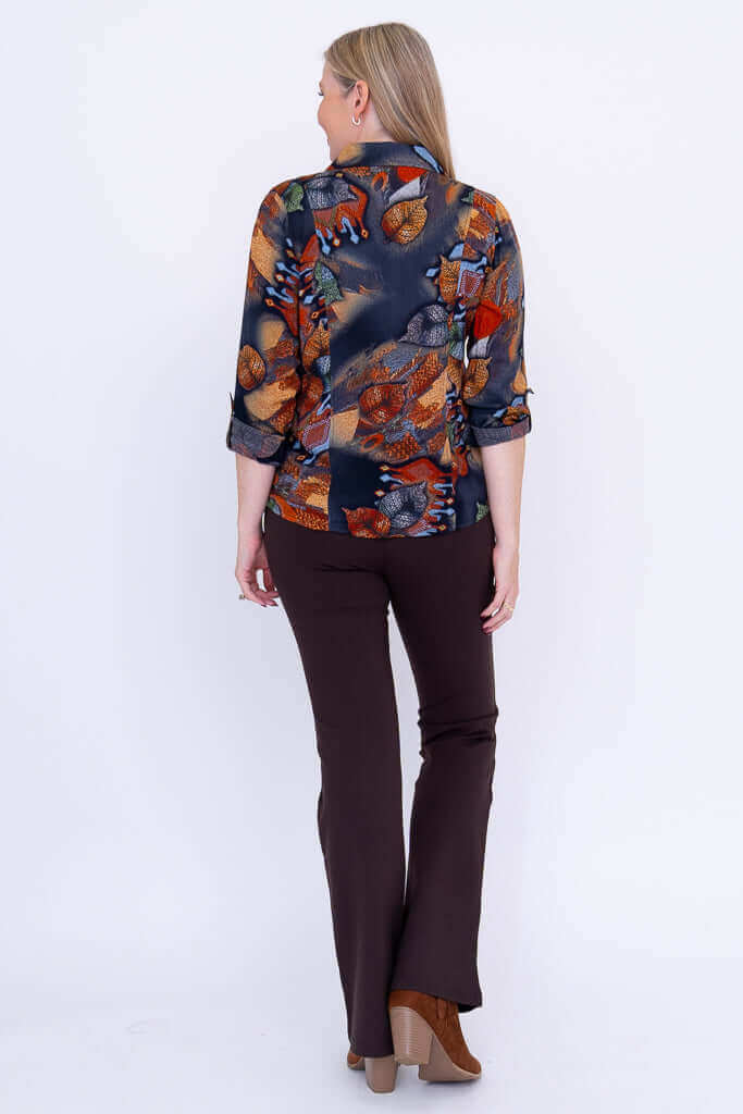 Back view of woman in botanical print button-up blouse and brown pants