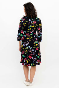 Back view of a woman in a black floral wrap dress with colorful botanical print