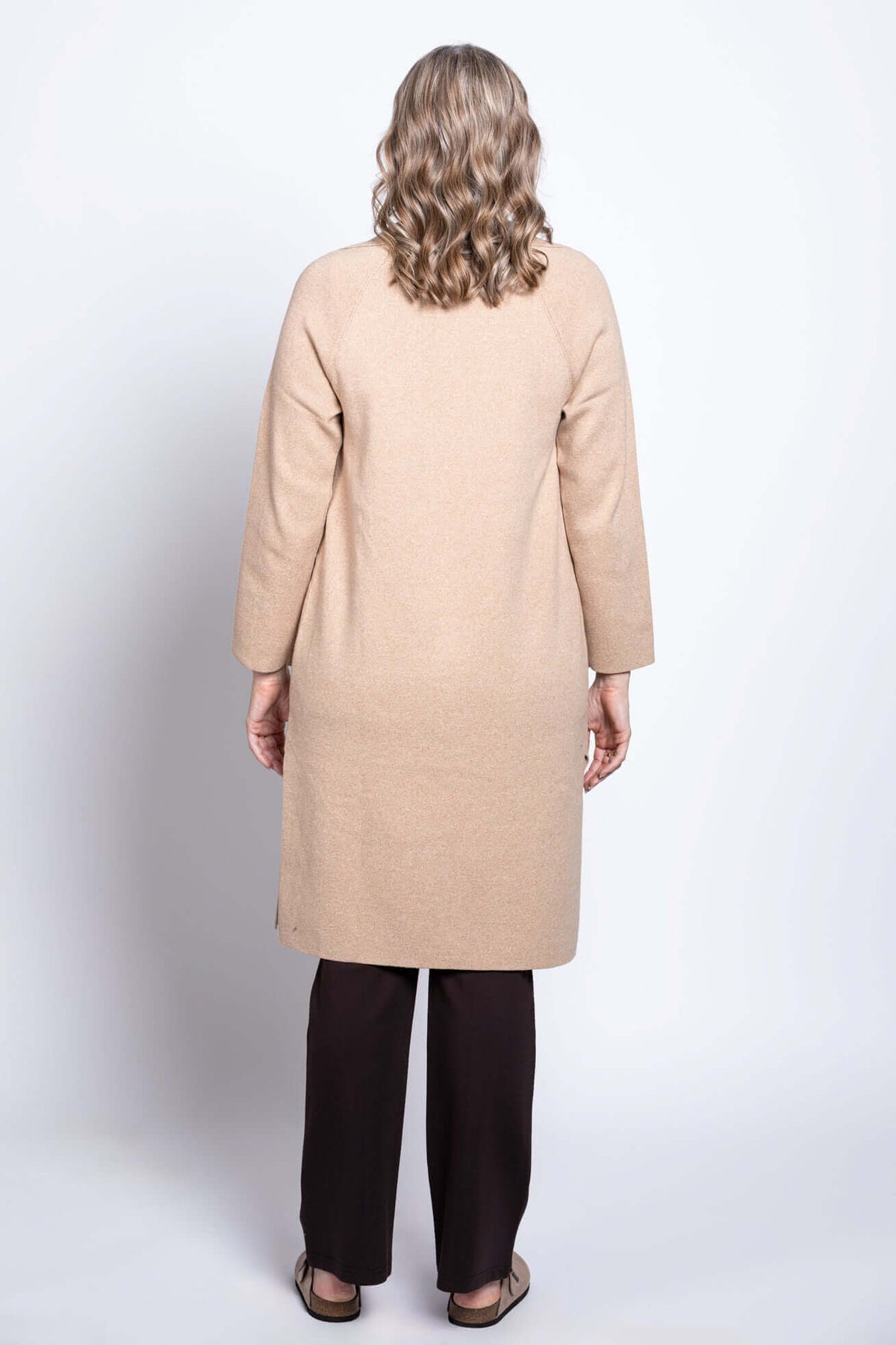 Back view of a woman showing the length and fit of a beige long cotton jacket