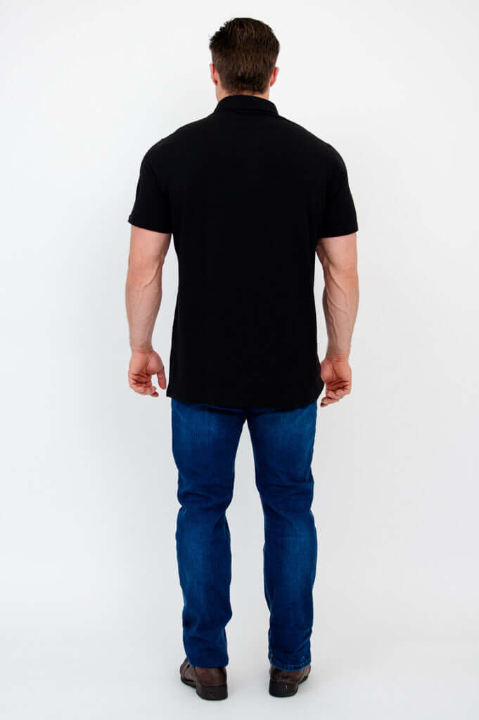 Back view of man wearing a black bamboo polo shirt with blue jeans