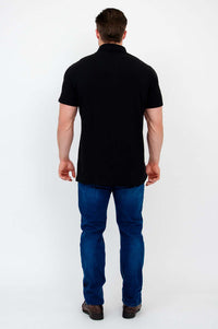 Back view of man wearing a black bamboo polo shirt with blue jeans