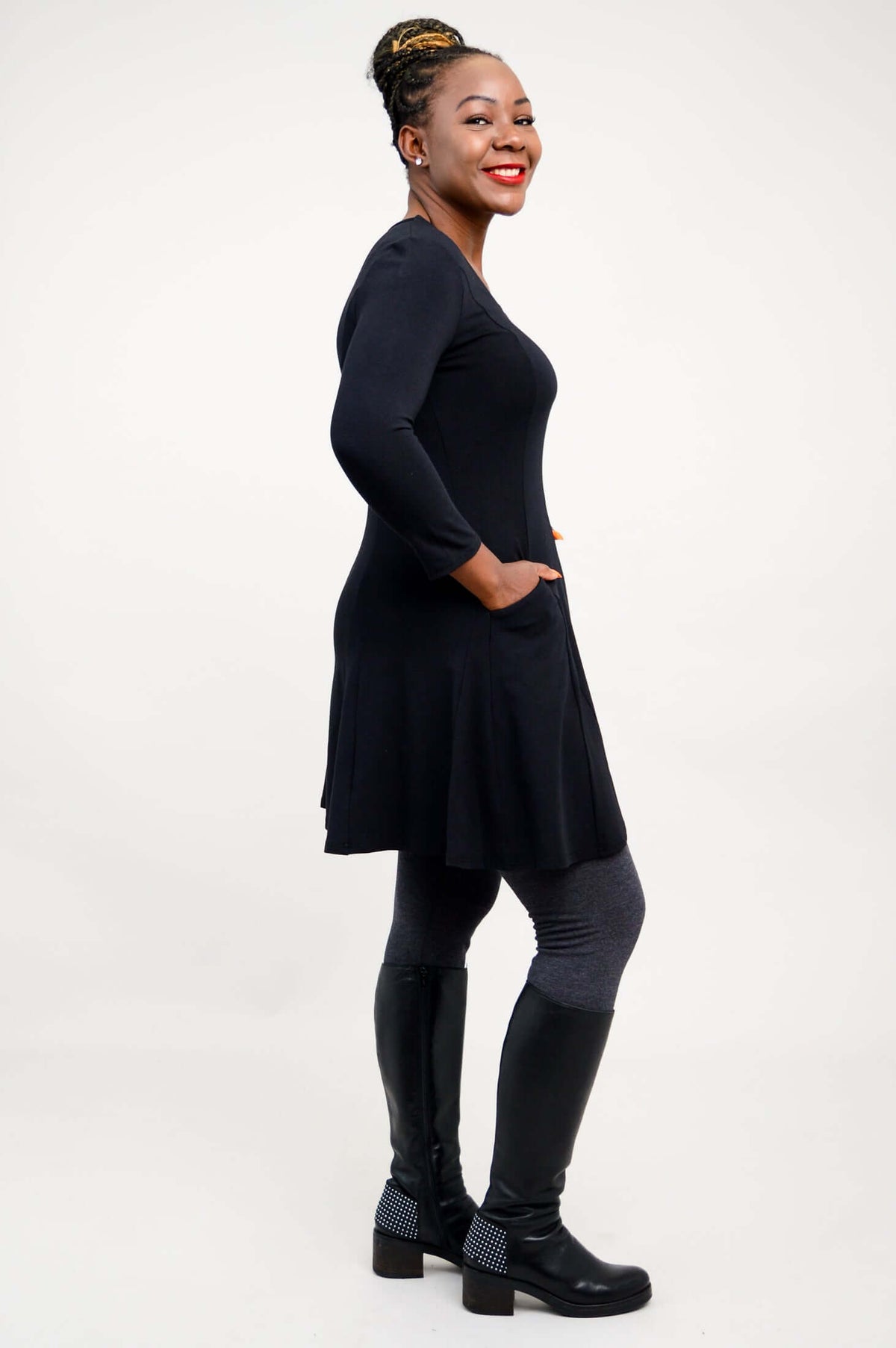 Back view of model wearing black tunic dress, grey leggings, and black boots