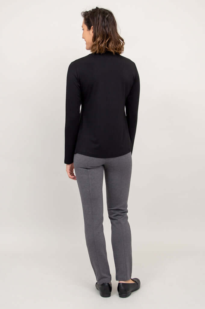 Back view of a woman wearing a black mock neck long sleeve top and gray pants