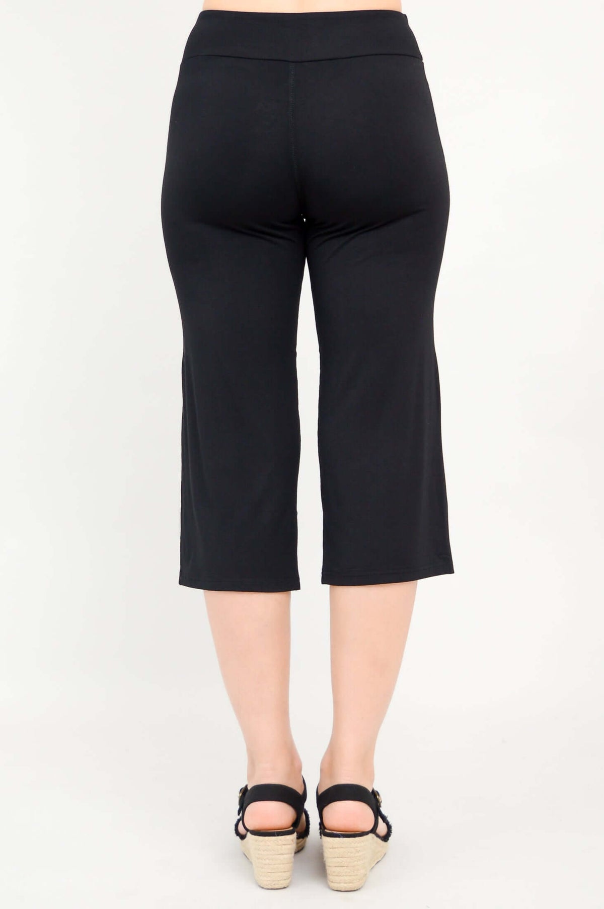 Back view of a woman wearing black yoga capri pants with black sandals