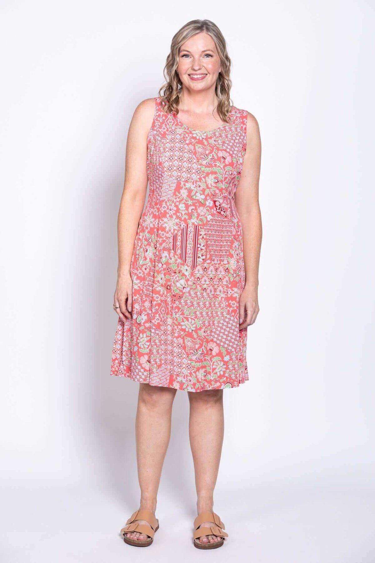 Woman showing the back of a coral floral patchwork dress with a tie-belt