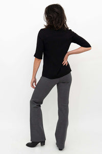 Woman modeling granite grey flare pants and black shirt, back view