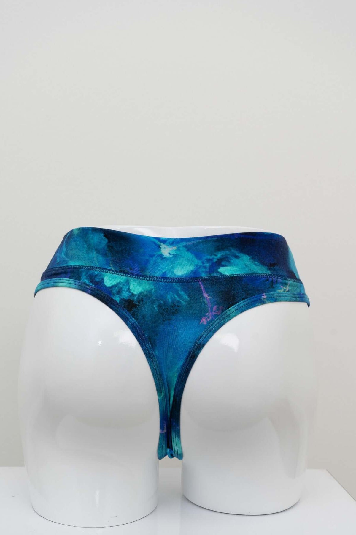 Back view of high rise blue watercolor bamboo thong on a mannequin