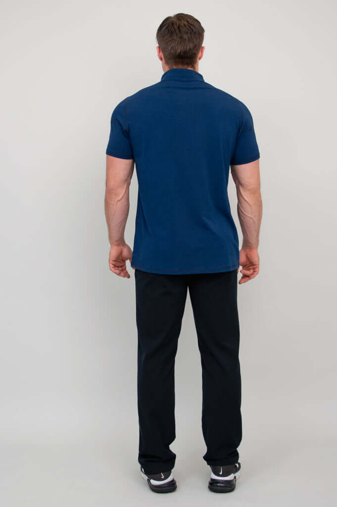 Back view of man wearing navy bamboo polo shirt and black pants