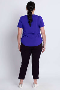 Back view of a woman wearing a purple scoop neck tee and black cropped pants
