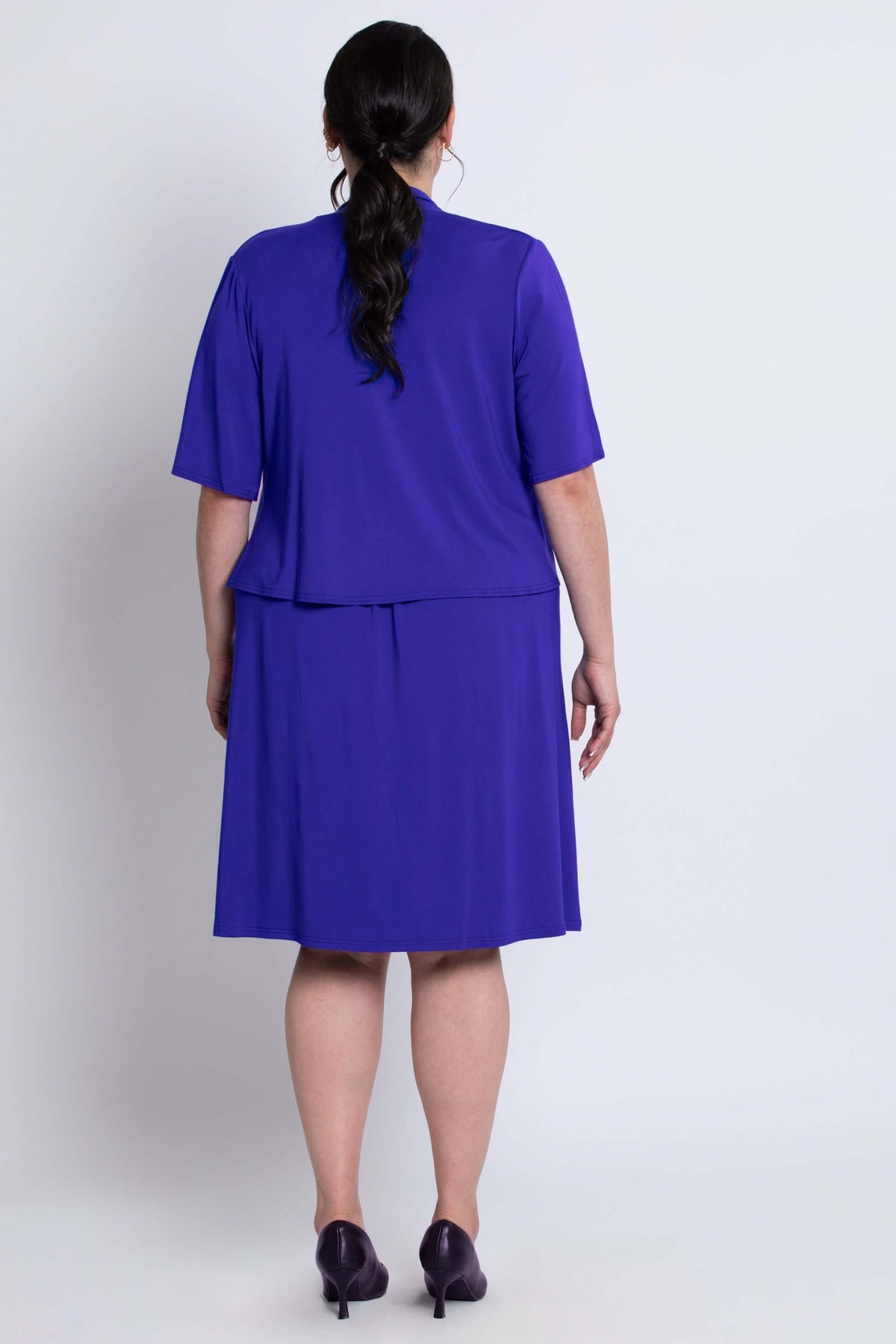 Back view showing the fit of the cobalt blue cropped jacket and dress on the model