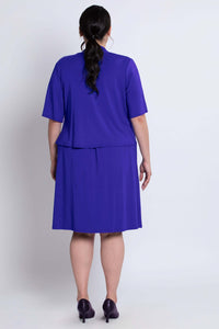 Back view showing the fit of the cobalt blue cropped jacket and dress on the model