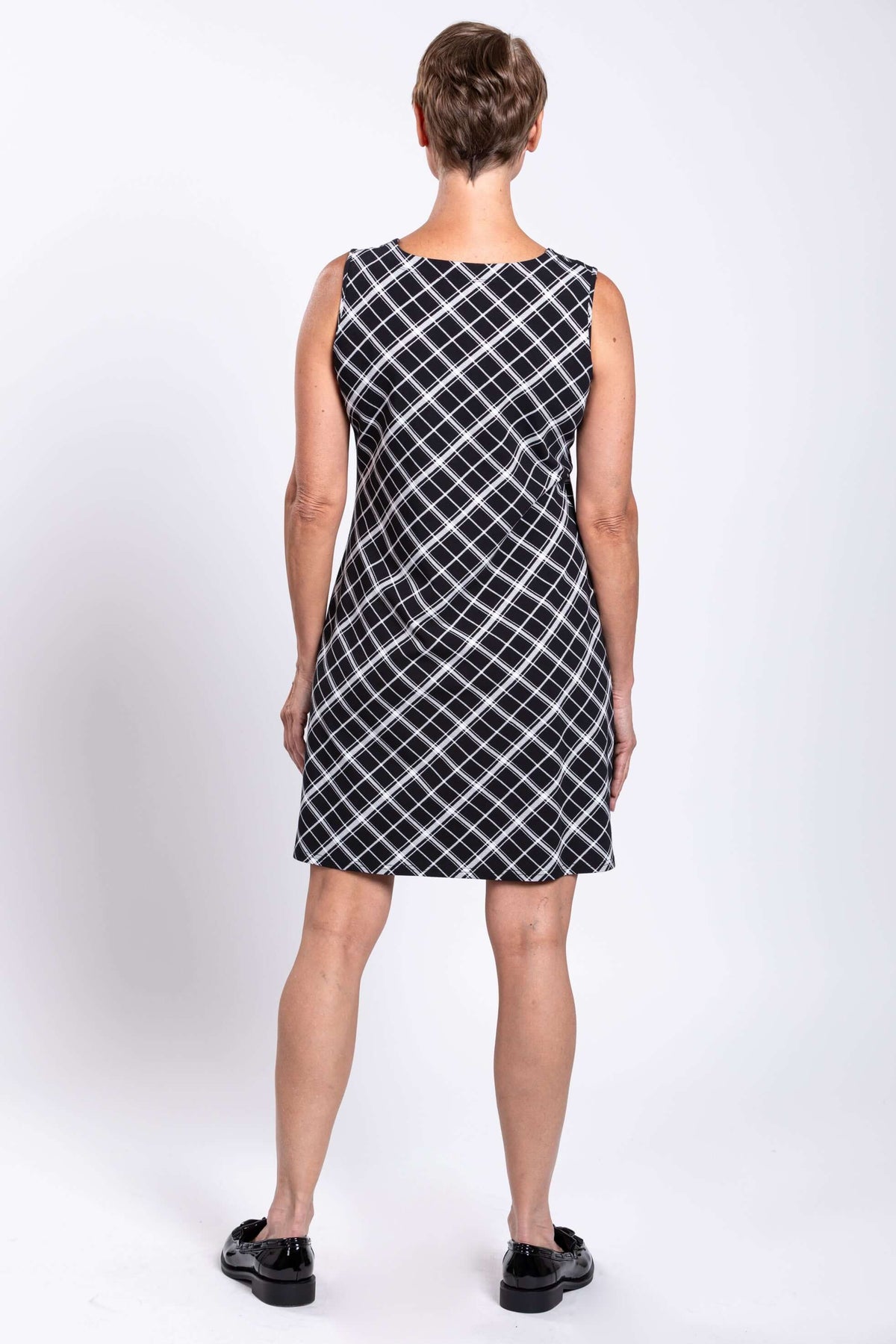 Back view of woman wearing sleeveless black and white plaid shift dress