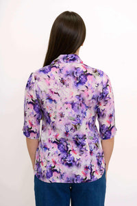 Back view of a woman wearing a purple and pink floral blouse with princess seams