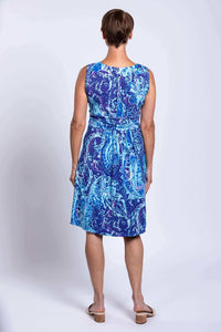 Back view of a sleeveless blue paisley dress worn by a woman