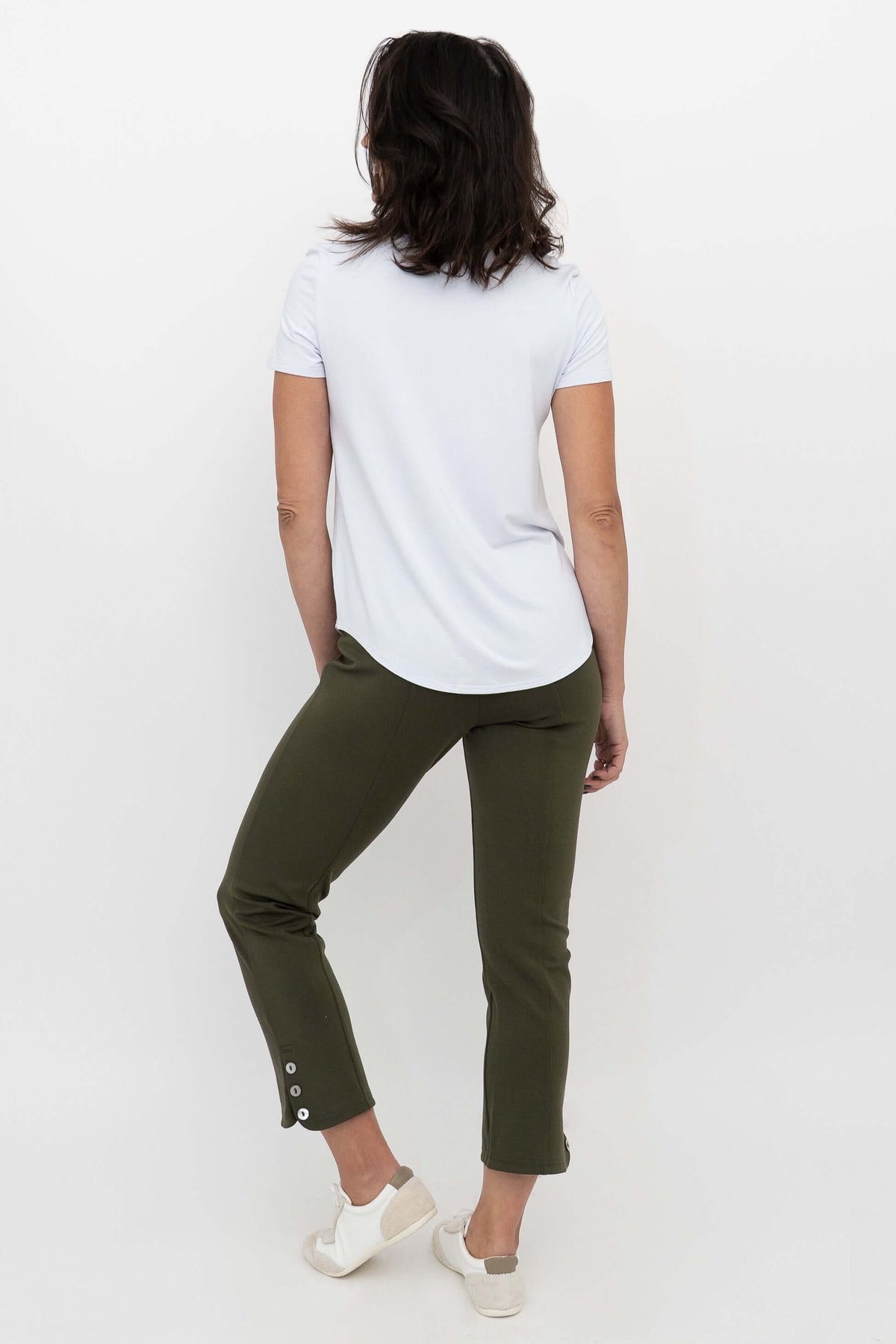 Back view of woman in olive green crop pants and white t-shirt, highlighting button detail