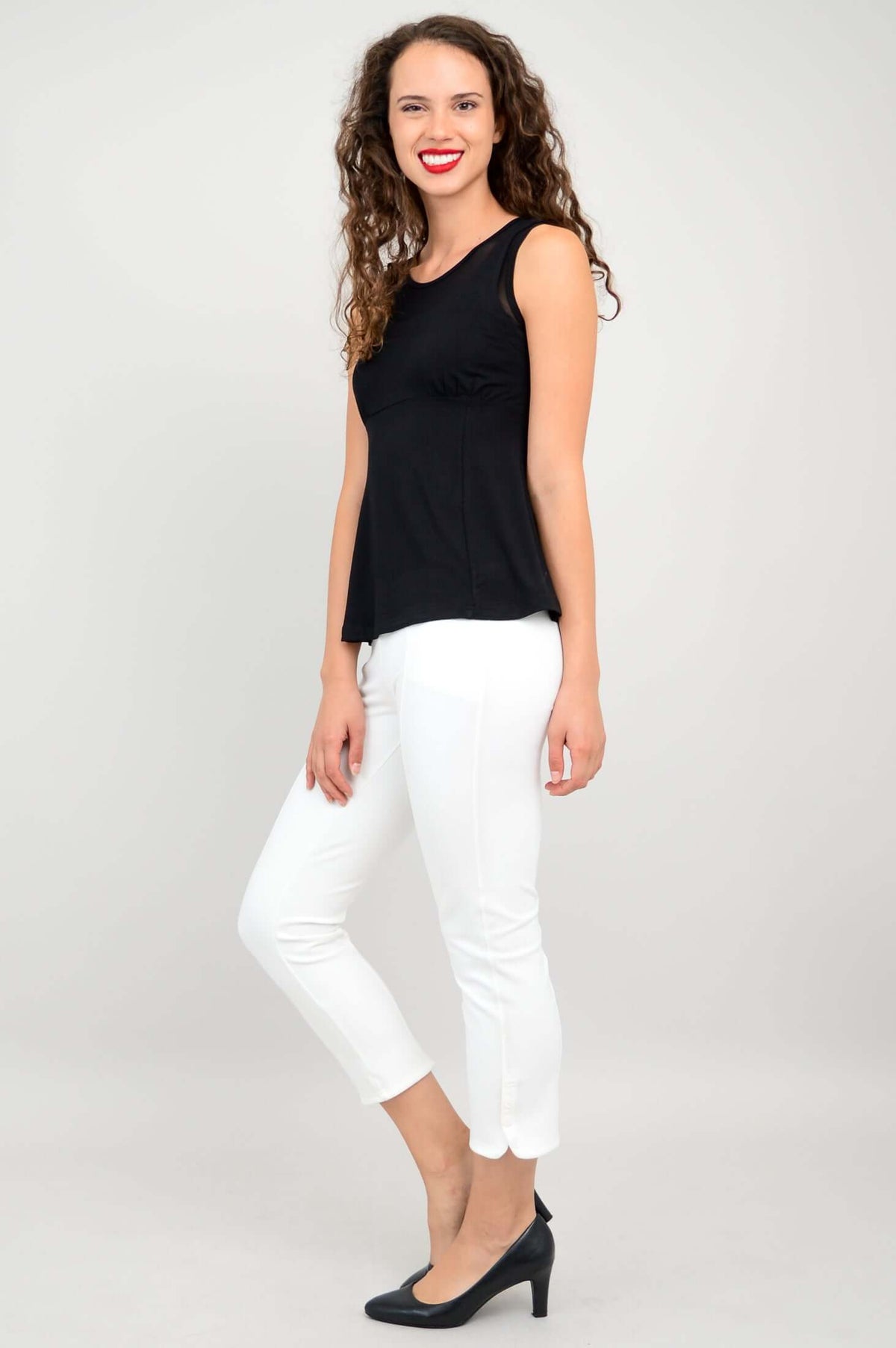 Back view of woman wearing black tank top with mesh panel and white pants