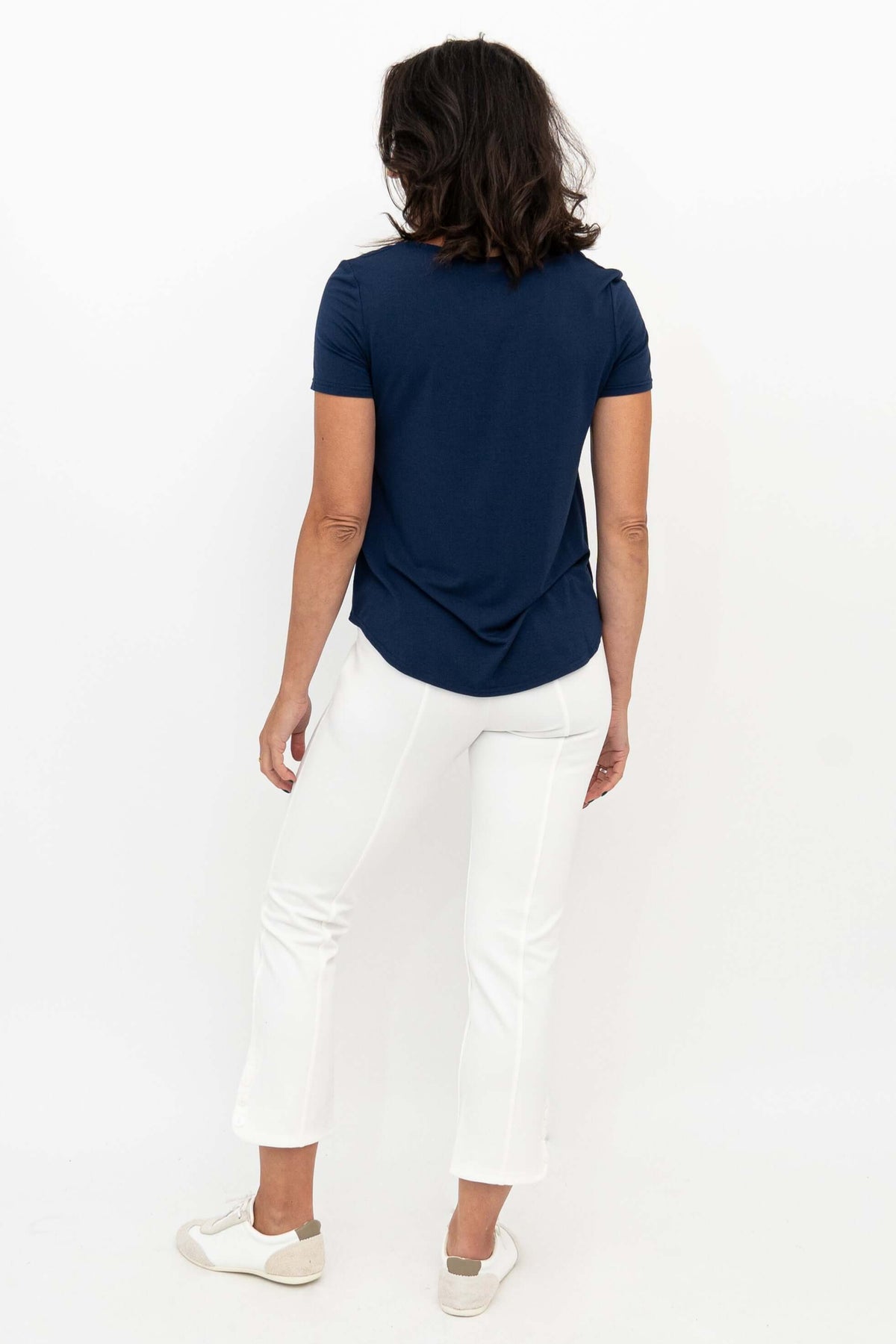 Back view of woman wearing white Nadine crop pants and navy tee