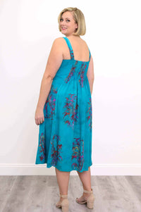 Back view of woman in an aqua blue midi dress with colorful floral accents and elastic back