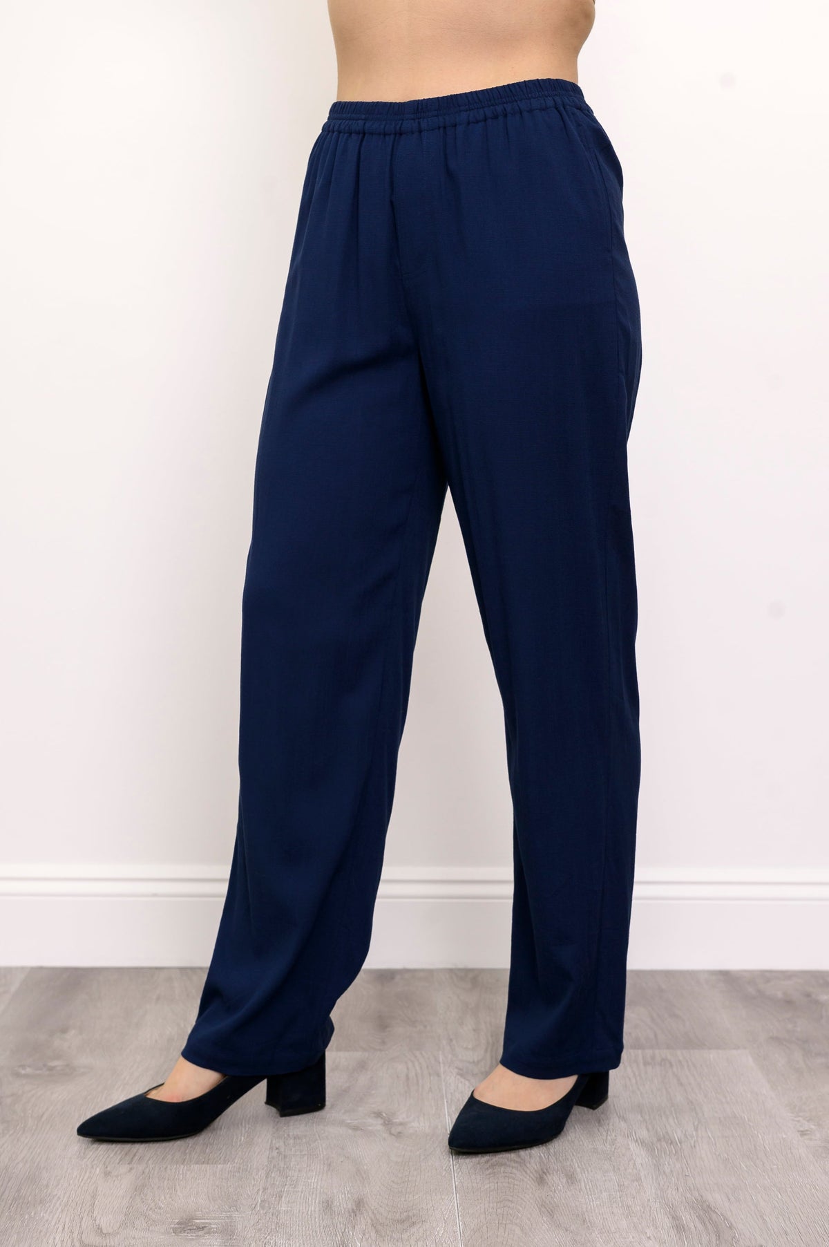 Close-up of woman wearing navy blue pants and navy blue heels on a white background