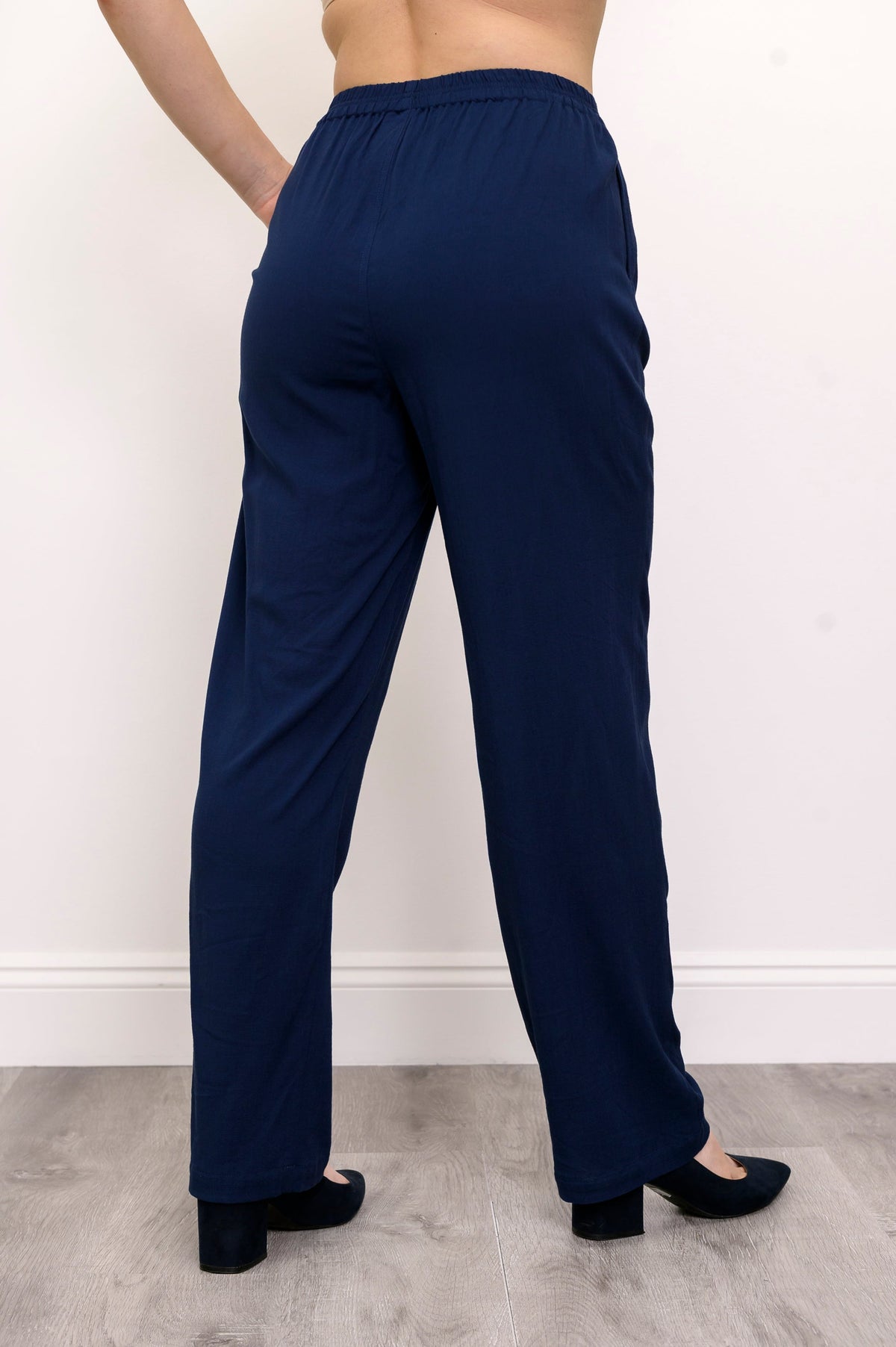 Close-up shot of woman wearing navy blue pants and navy blue heels on a white background