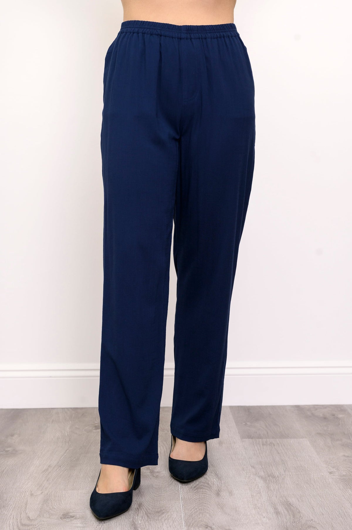 Close-up of woman wearing navy blue pants and navy blue heels on a white background