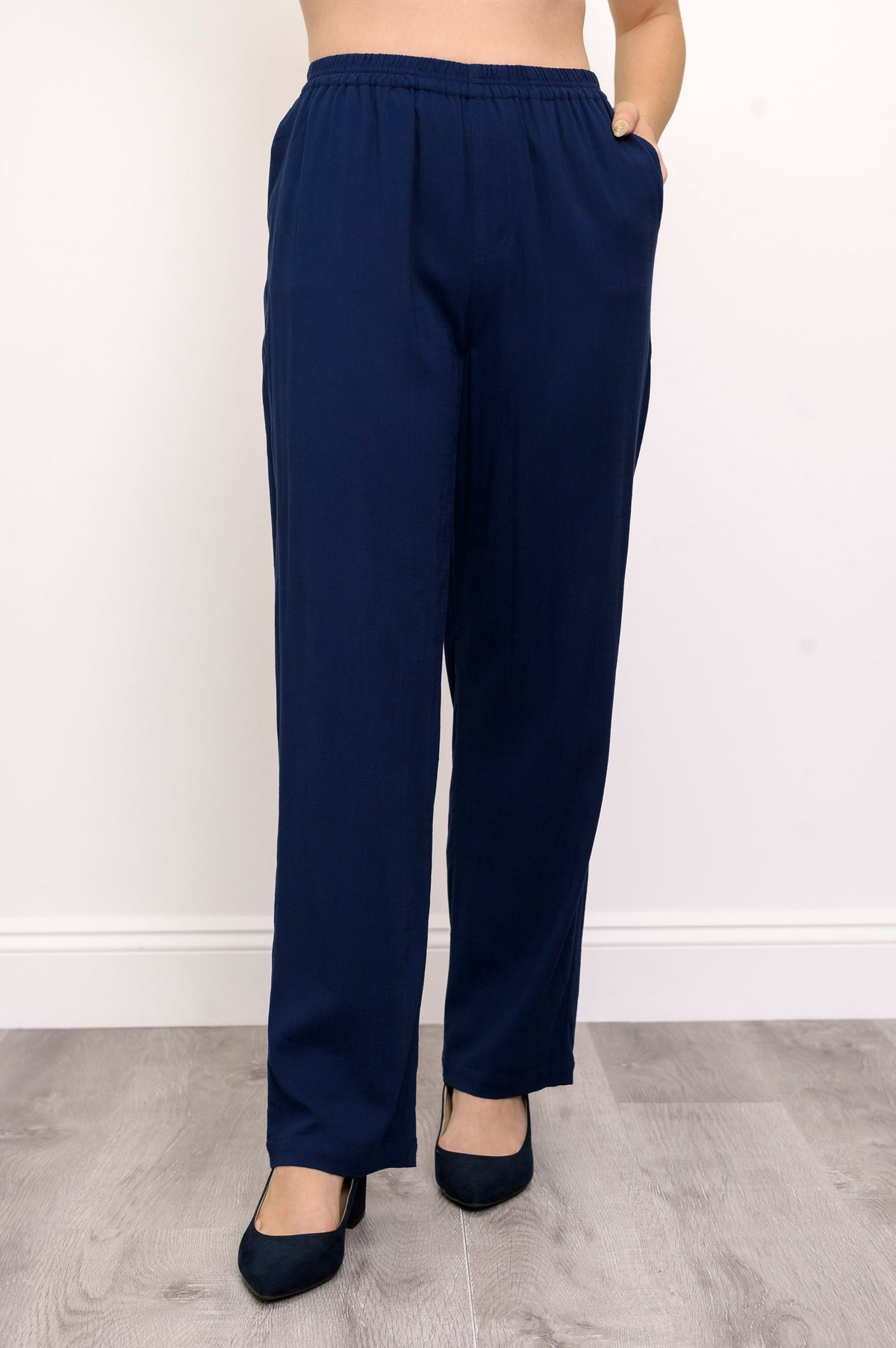 Close-up of woman wearing navy blue pants and navy blue heels on a white background