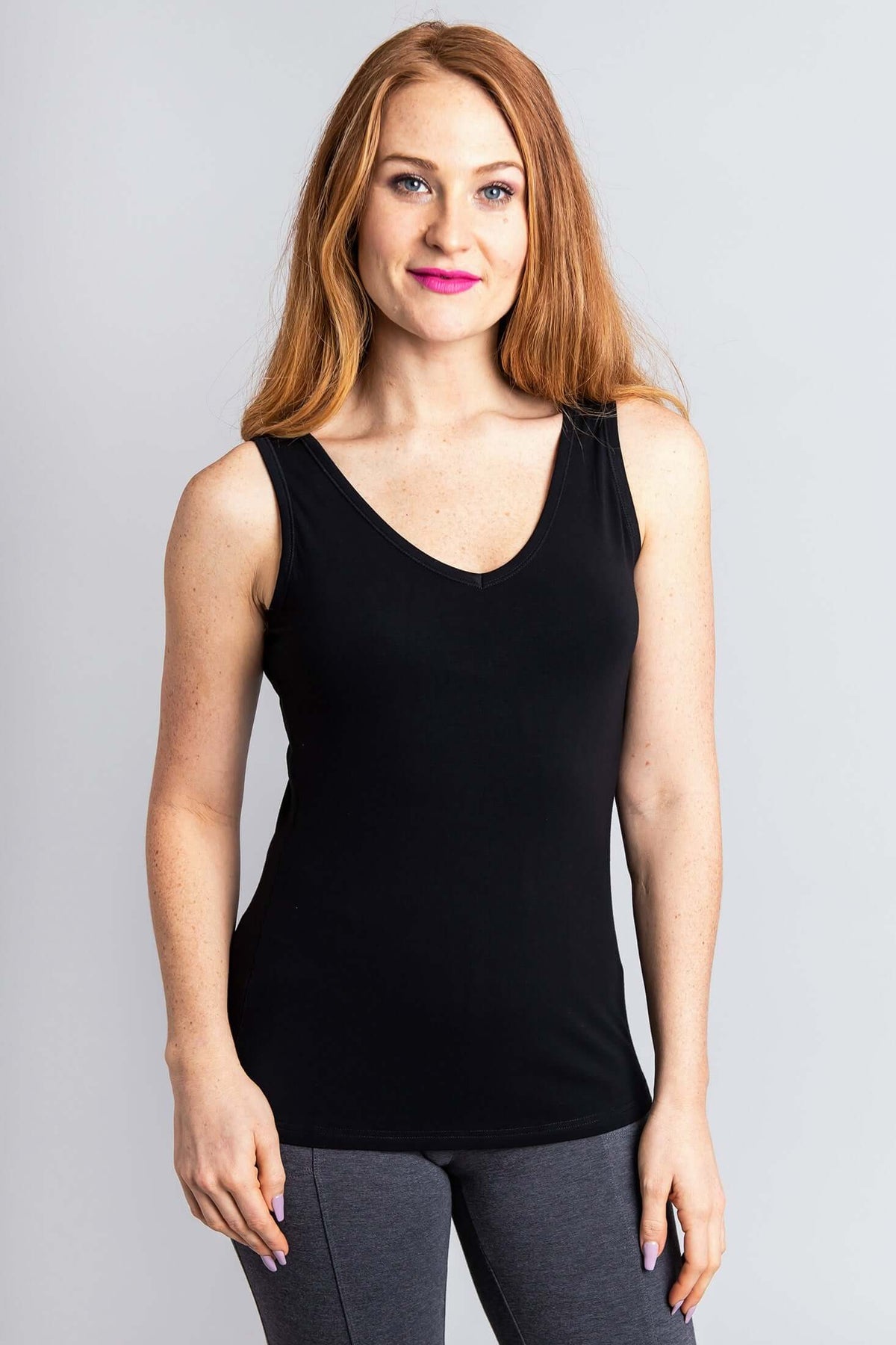 Woman modeling a black bamboo tank top with a V-neckline and grey leggings