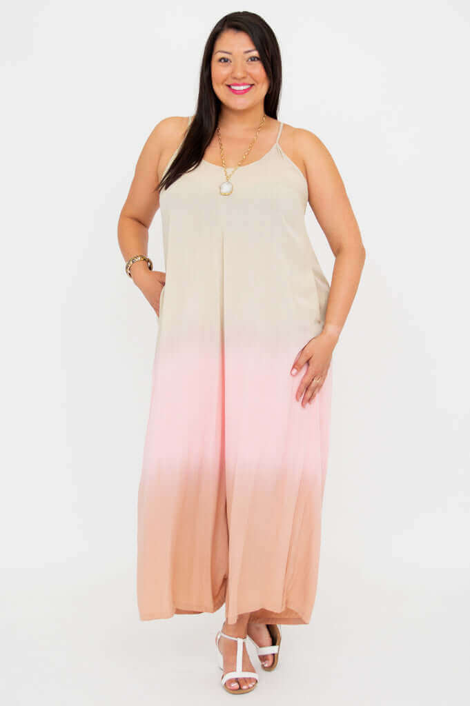 Woman standing confidently in blush ombre jumpsuit with white sandals, white background
