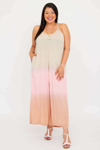 Front view of woman smiling in blush ombre jumpsuit with adjustable straps, white background
