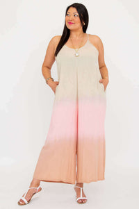Woman looking to the side in a blush ombre jumpsuit, hands in pockets, white background