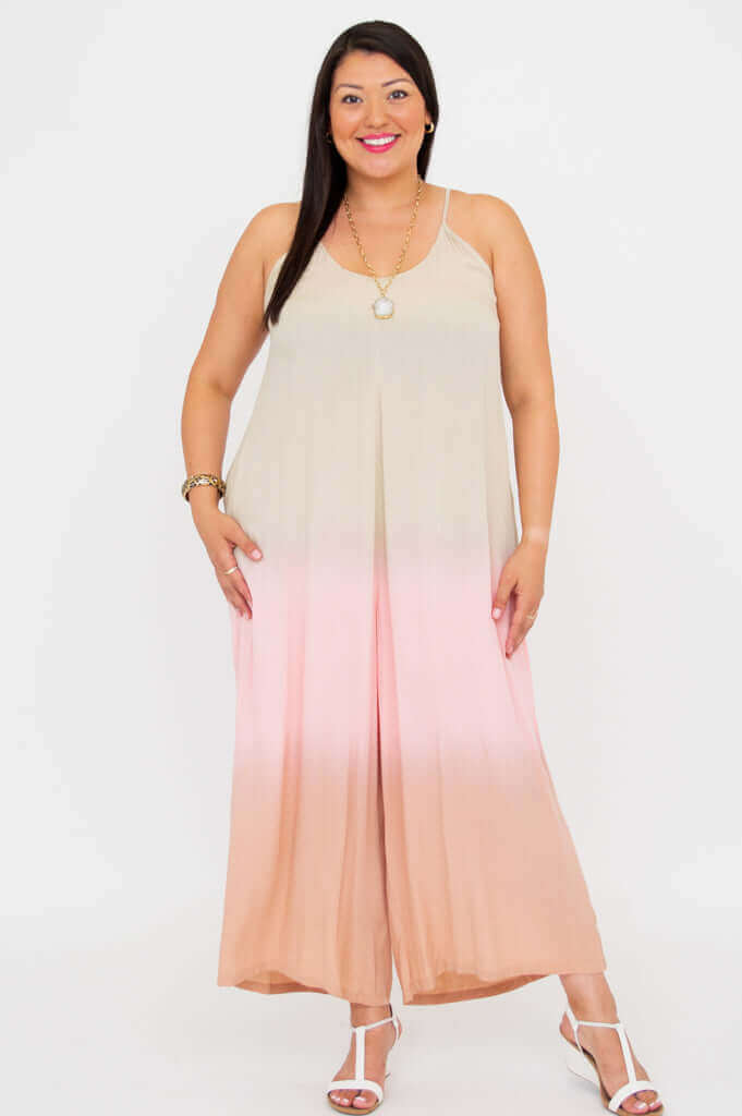 Woman smiling brightly in blush ombre wide-leg jumpsuit, standing against white backdrop