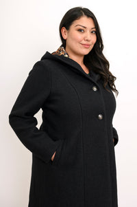 Close-up side view of woman wearing black boiled wool coat with pockets and silver buttons