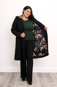 Woman showing off the black and multicolor floral satin lining of her long black coat