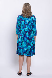 Rear view of woman wearing an ocean print blue knee-length dress against a white background
