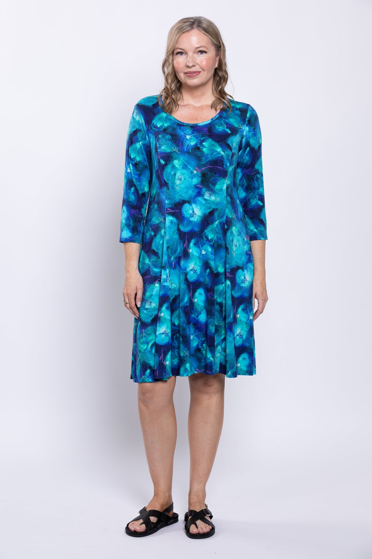 Full body picture of woman wearing a blue ocean print dress on a white background