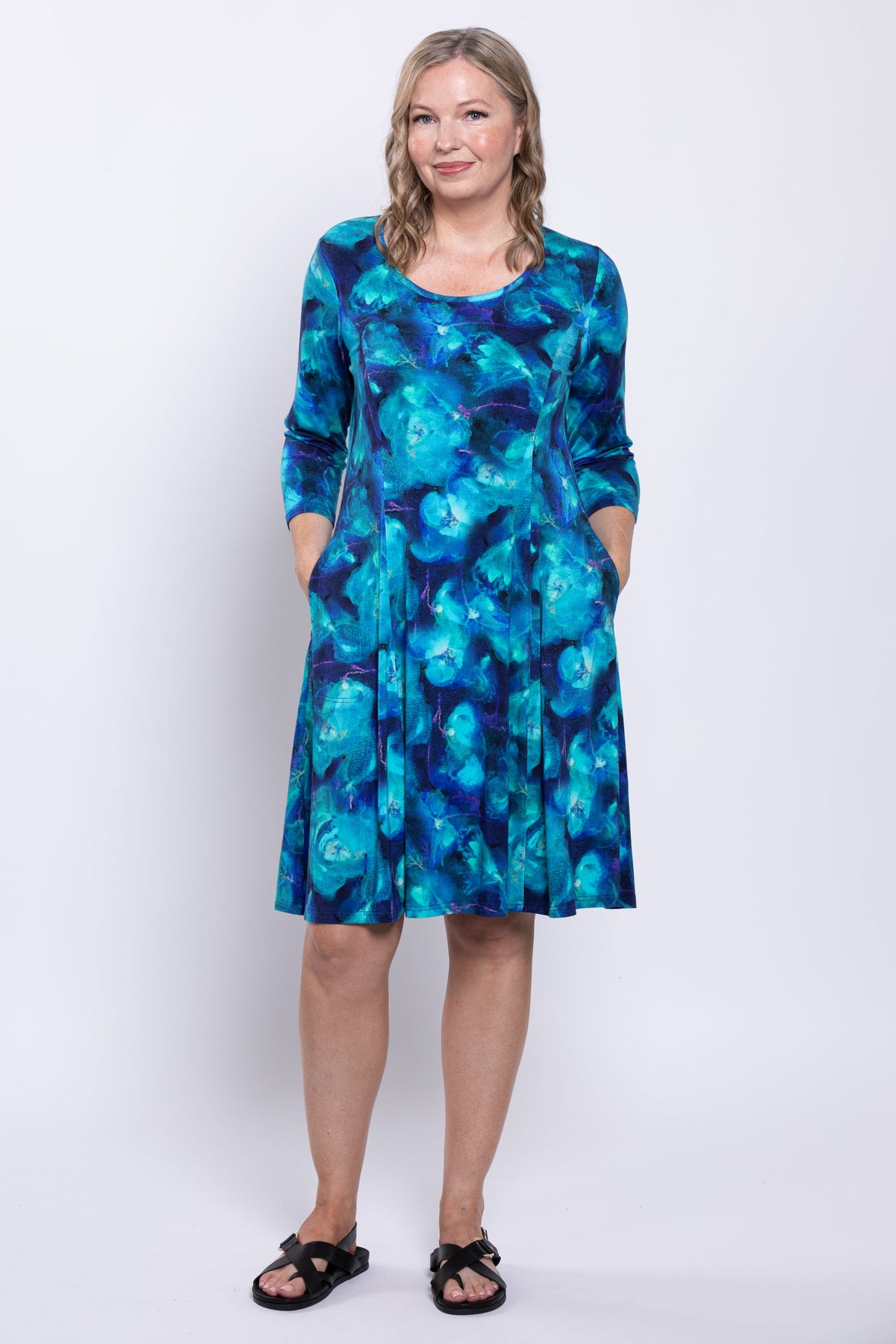 full body view of woman modeling a blue printed dress with her hands in her pockets