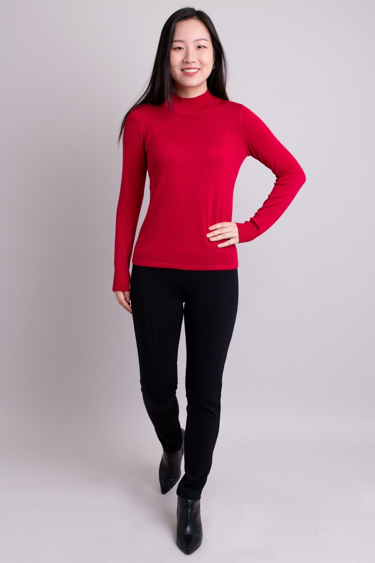 Women's red long-sleeve mock neck sweater worn with black pants. Made with sustainable and natural fibers, fair-trade.