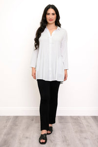 Full body view of woman wearing white button up blouse and black pants against a white background