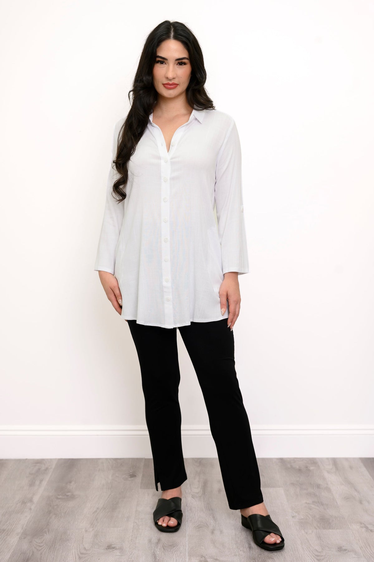 Full body front view of woman wearing a white collared blouse and slim black pants