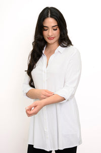 Woman touching the sleeve of her white collared-button up blouse against a white background