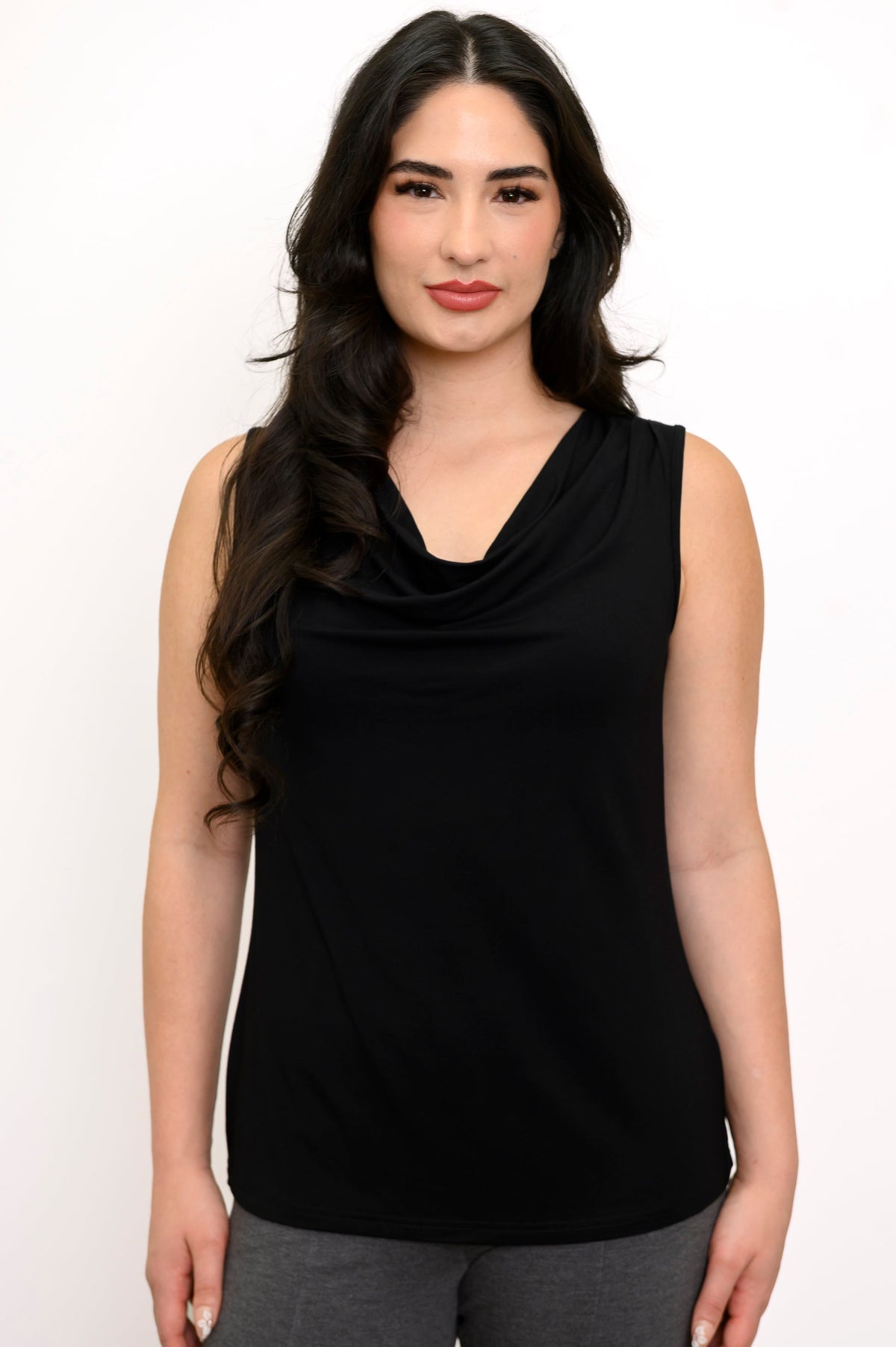 Close up of woman wearing a black cowl neck sleeveless top and grey pants