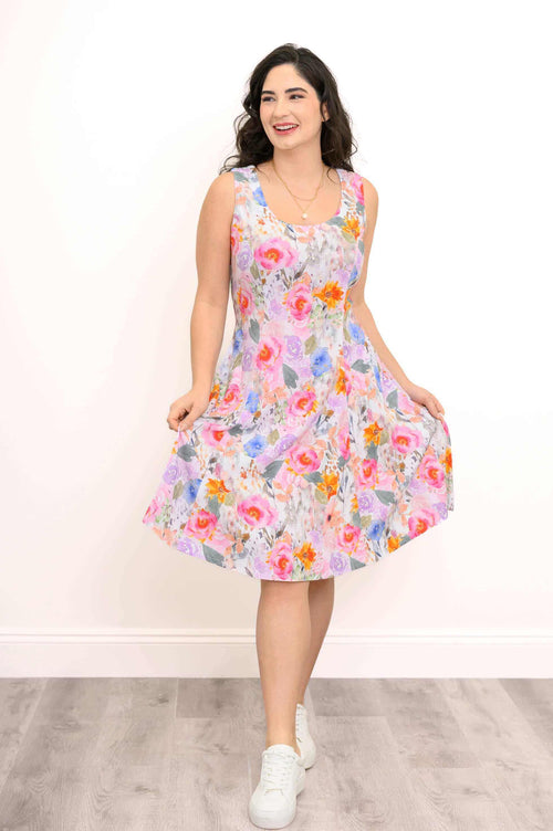 Woman smiling in a scooped neck floral A-line dress holding out the skirt