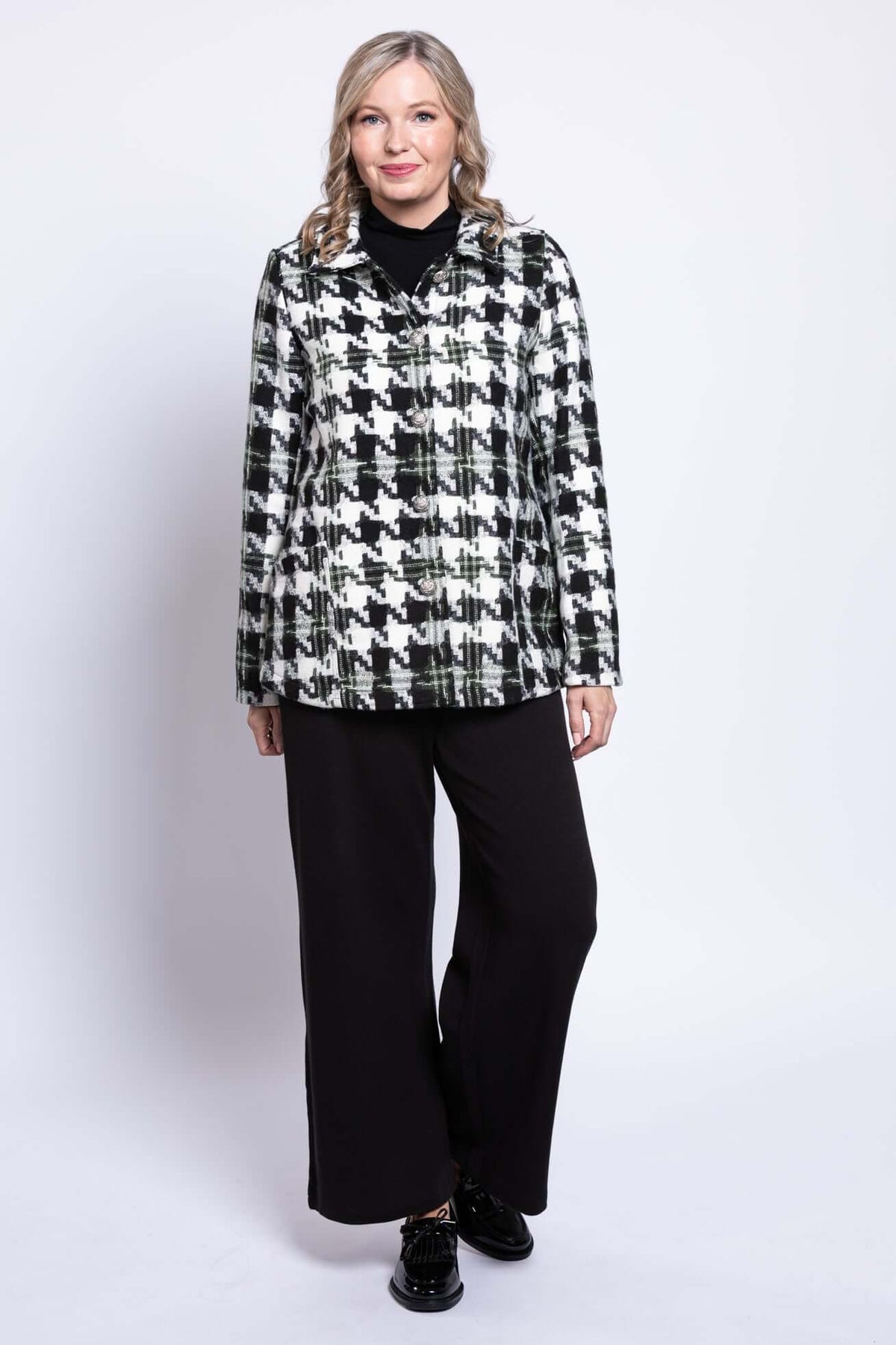 Woman standing facing forward in black and white houndstooth button-up coat