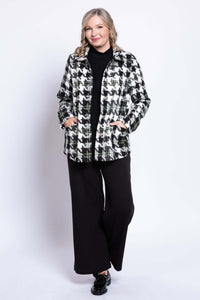 Angle view of woman in black and white houndstooth coat with hands in pockets