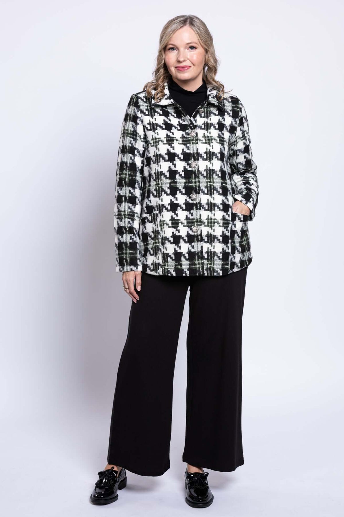 Woman in black and white houndstooth coat with relaxed posture, front view